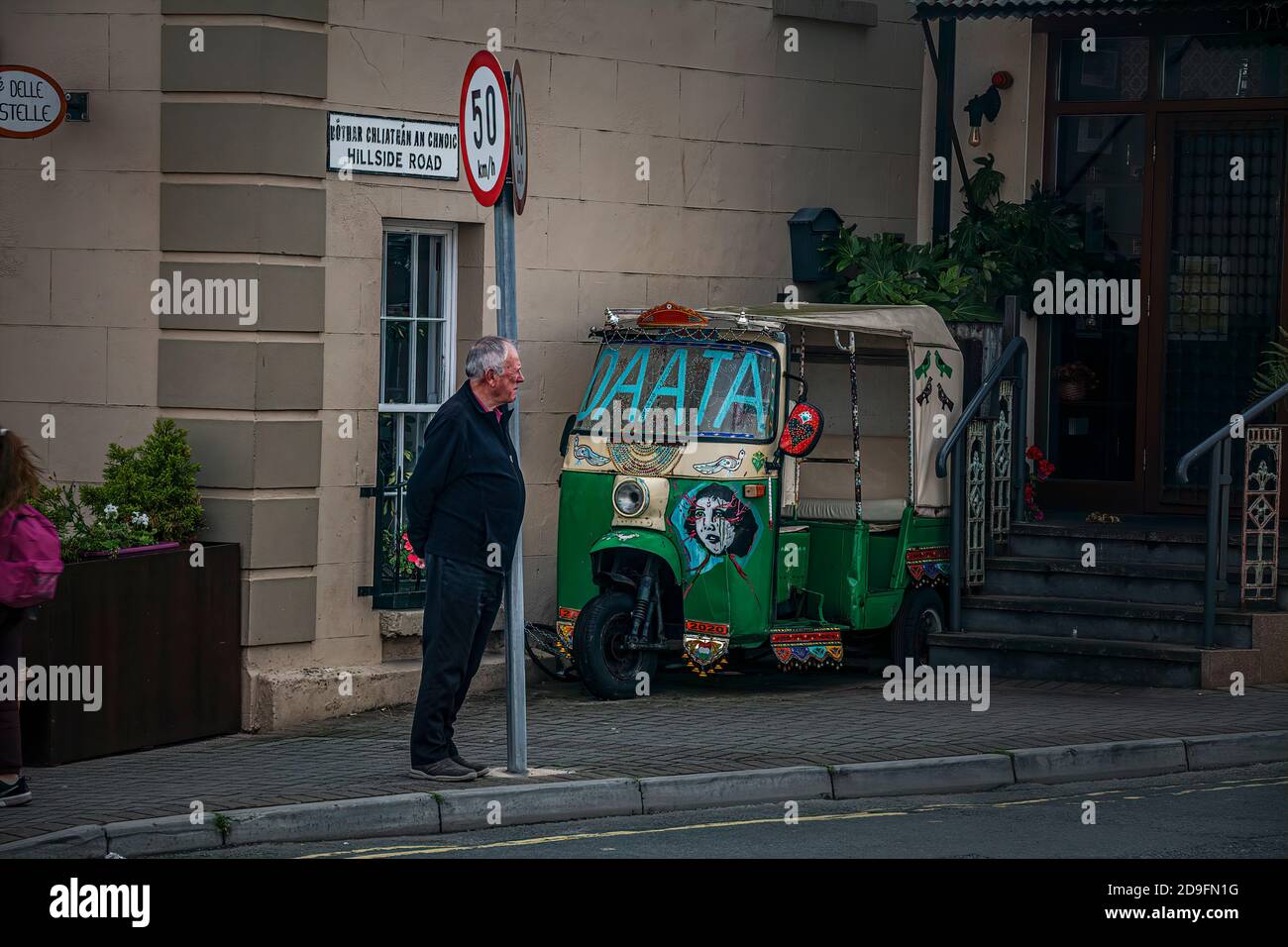 Verboten. Begrenzungszeichen und alter Mann, der hinter ihm schaut. Konzept. Älterer Mann, der sich an eine Säule des Straßenschilds lehnt. Stockfoto