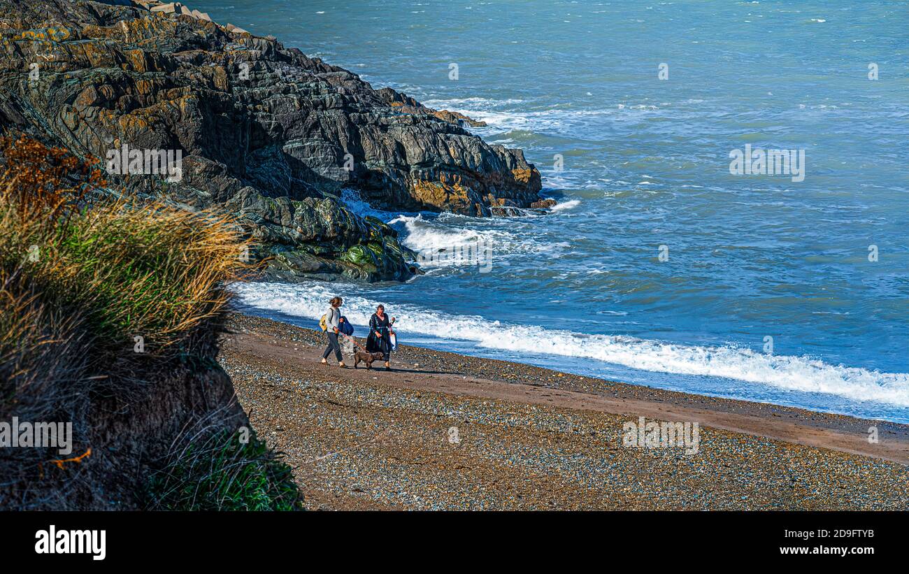 Alltag. Zwei Damen mit Hund, die am kleinen Meeresstrand am Meer entlang spazieren. Stockfoto