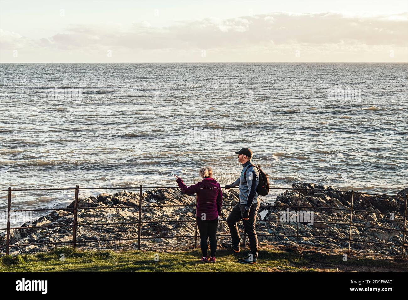 Alltag. Ein Paar mittleren Alters, das vom felsigen Strand aus auf das Meer blickt. Stockfoto