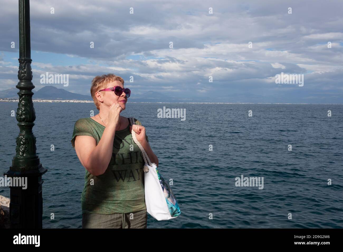 Reife Frau in Sonnenbrille am Ufer des Meeres Schaut zur Seite Stockfoto