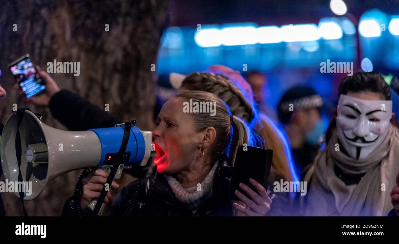 Westminster, London, Großbritannien. November 2020. Am 5. November fand in der Nähe des Parlaments ein regierungsfeindlicher Protest statt, der sich mit dem Schießpulver-Komplott von 1605 und dem Versuch, das Gebäude zu zerstören, verband. Demonstranten tragen oft "V für Vendetta"-Masken mit einer Ähnlichkeit zu Guy Fawkes. Da das Datum auch der erste Tag der nationalen Sperre ist, haben sich Anti-Lockdown-Demonstranten angeschlossen. Eine starke Polizeipräsenz reduzierte die Auswirkungen des Ereignisses, das sich vor dem Trafalgar Square versammelt hatte. Weibliche Gesänge durch Megaphon Stockfoto