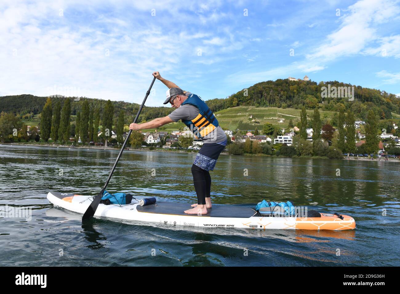 Mann paddeln auf einem SUP den Rhein hinunter in der Schweiz Stockfoto