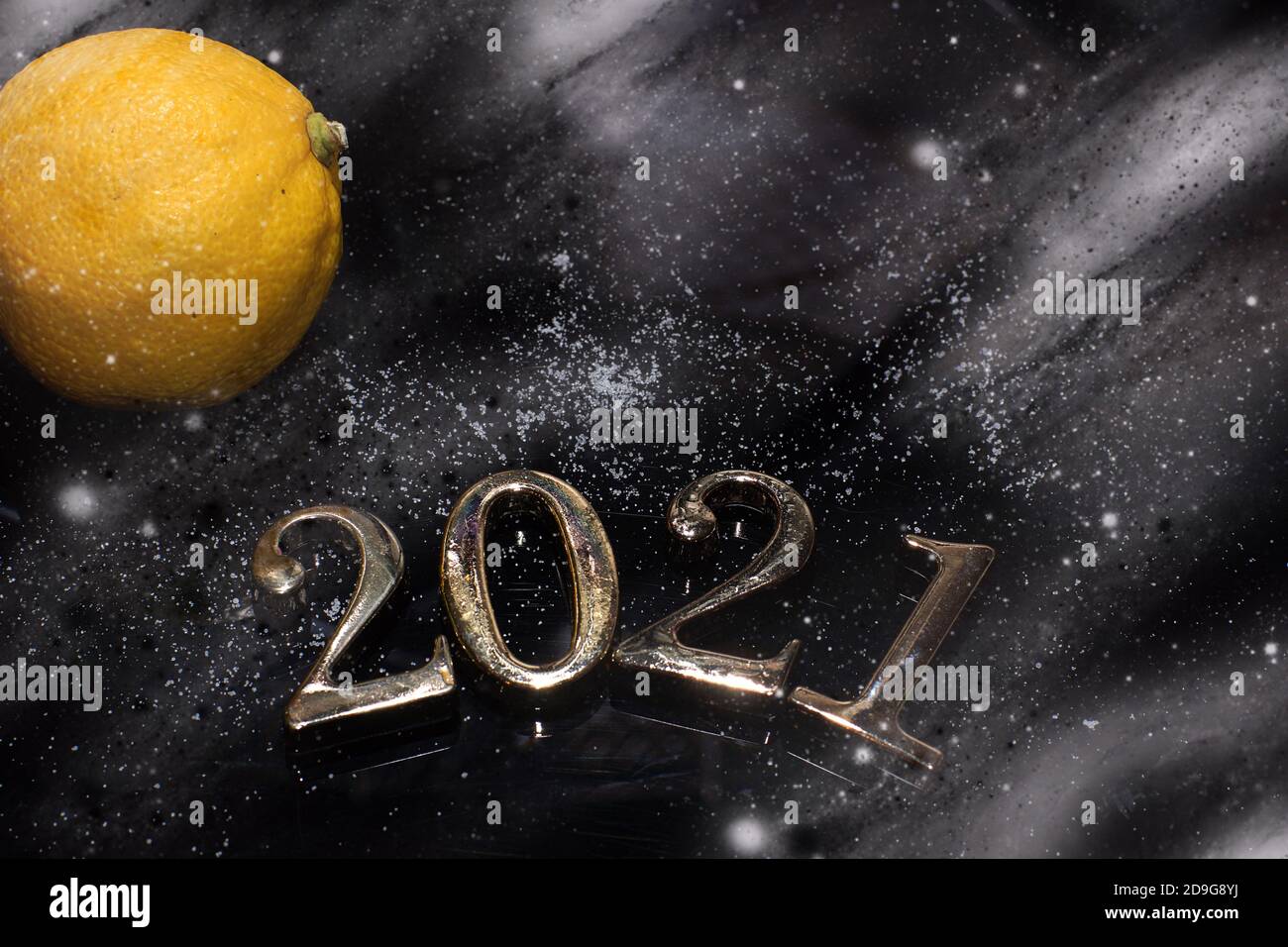 Ziffern 2021 mit Schnee bedeckt neben Zitrone auf dunklem Hintergrund. Stockfoto