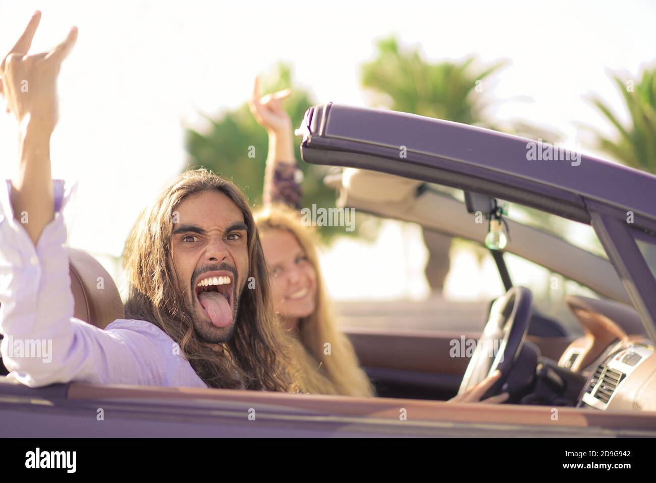 Glücklich junges Paar mit Spaß in Cabrio Sportwagen. Paar hören Rockmusik. Urlaub, Reise und Beziehungskonzept. Fokus auf Mann f Stockfoto