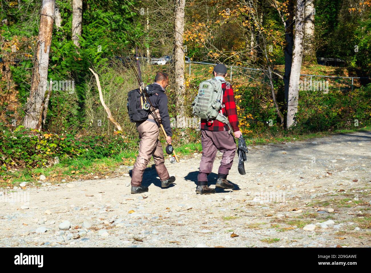 Zwei Fischer, die Hüftwader tragen und Angelruten tragen, gehen zurück zum Parkplatz. Mission, B. C., Kanada. Stock Foto. Stockfoto