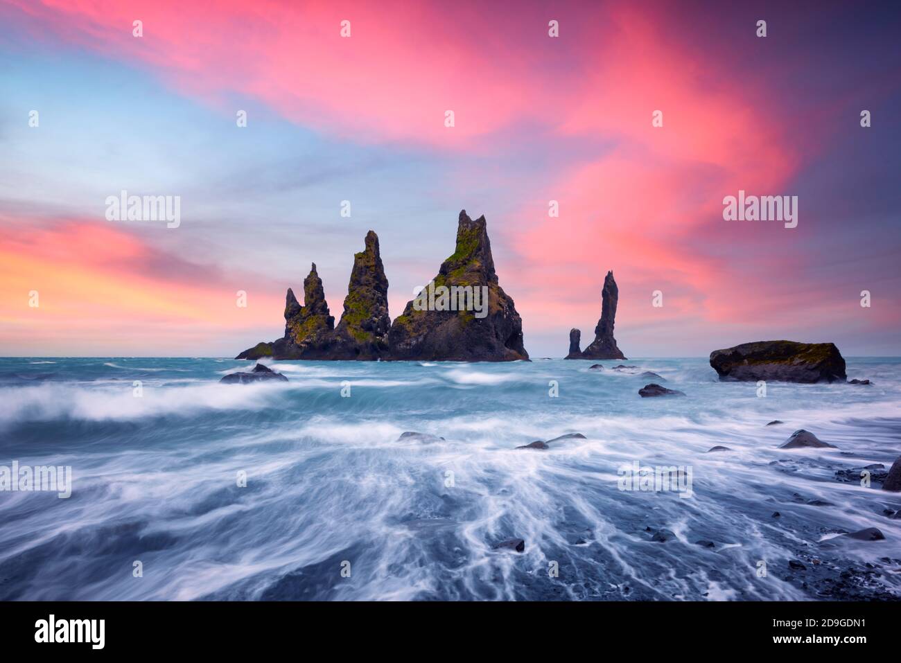 Basalt Felsformationen Troll Zehen am schwarzen Strand mit rosa Sonnenuntergangswolken. Großer lila Himmel leuchtet auf dem Hintergrund. Reynisdrangar, Vik, Island Stockfoto Basalt Felsformationen Troll Zehen am schwarzen Strand mit rosa Sonnenuntergangswolken. Großer lila Himmel leuchtet auf dem Hintergrund. Reynisdrangar, Vik, Island Stockfoto