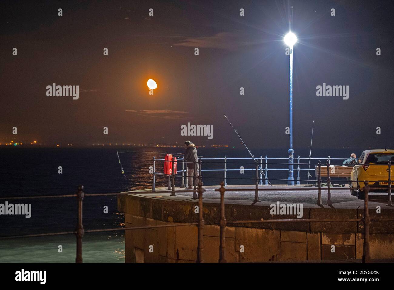Murmbles, Swansea, Großbritannien. November 2020. Fischer nutzen die ruhigen, aber kalten Wetterbedingungen am Parkplatz Knab Rock in Mumbles bei Swansea an diesem Abend unter einem schwingenden, feinem Mond. Quelle: Phil Rees/Alamy Live News Stockfoto