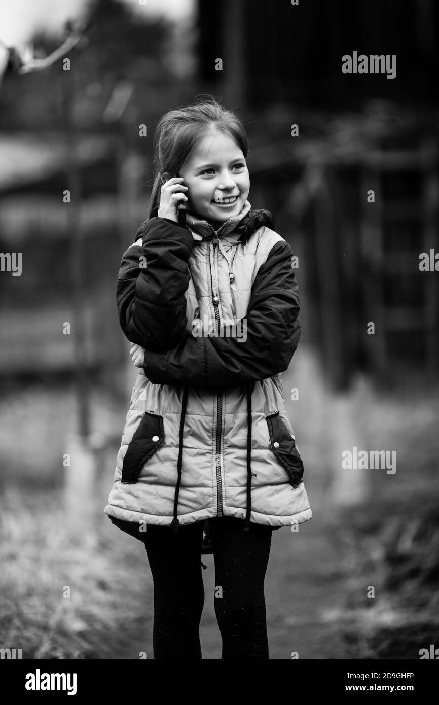 Kleines Mädchen im Gespräch auf dem Handy, im Freien. Schwarzweiß-Fotografie. Stockfoto