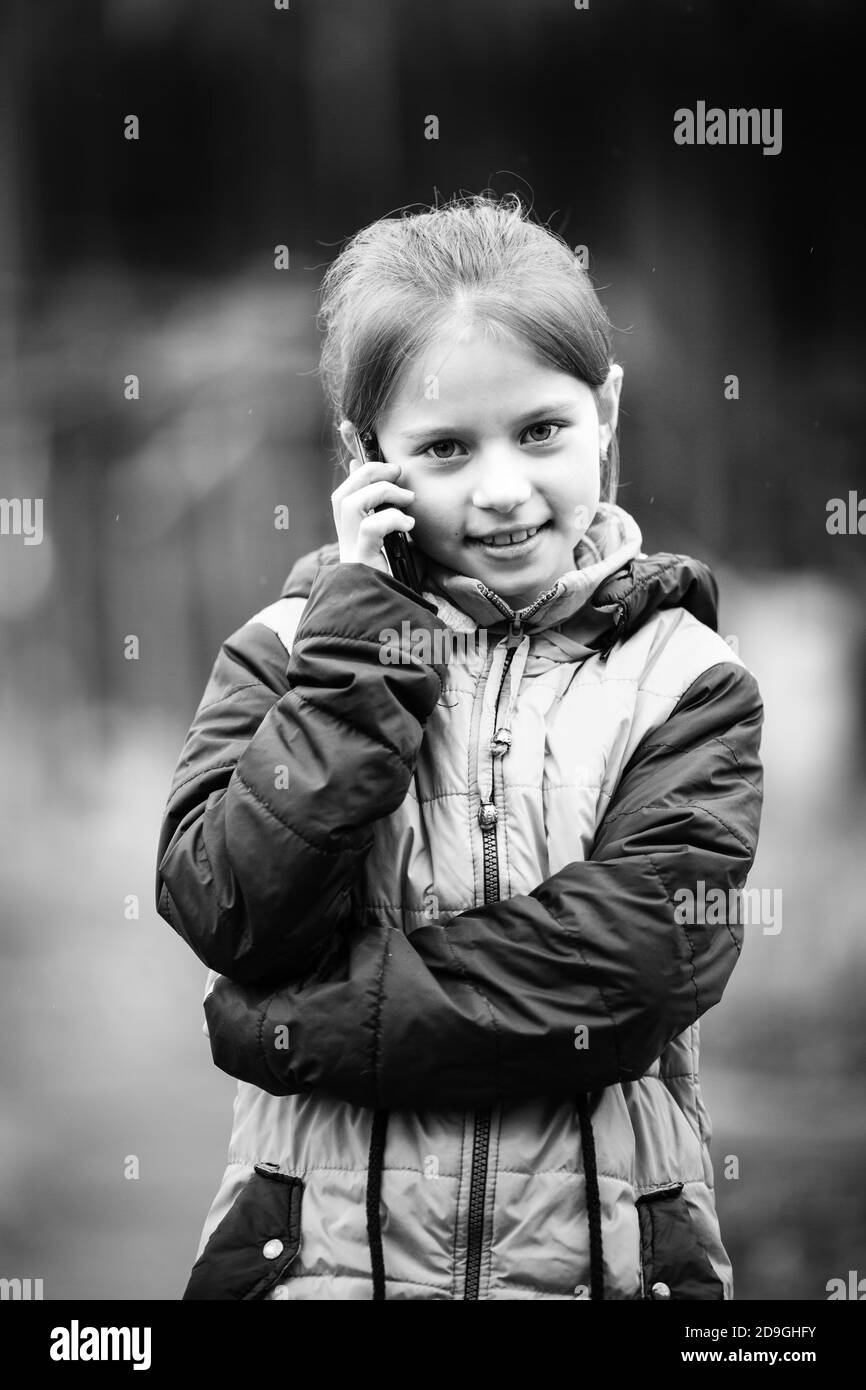 Portrait des kleinen Mädchens, das am Telefon spricht. Schwarzweiß-Fotografie. Stockfoto