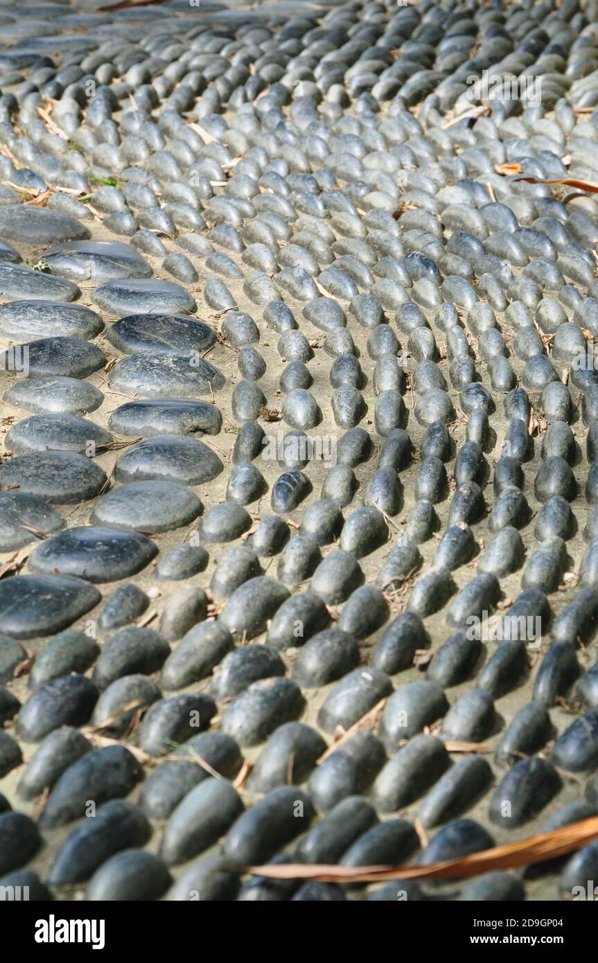 Perspektivische Ansicht eines gepflasterten Gesteinsfusspfades aus glatten abgerundeten Kieselsteinen. Stockfoto