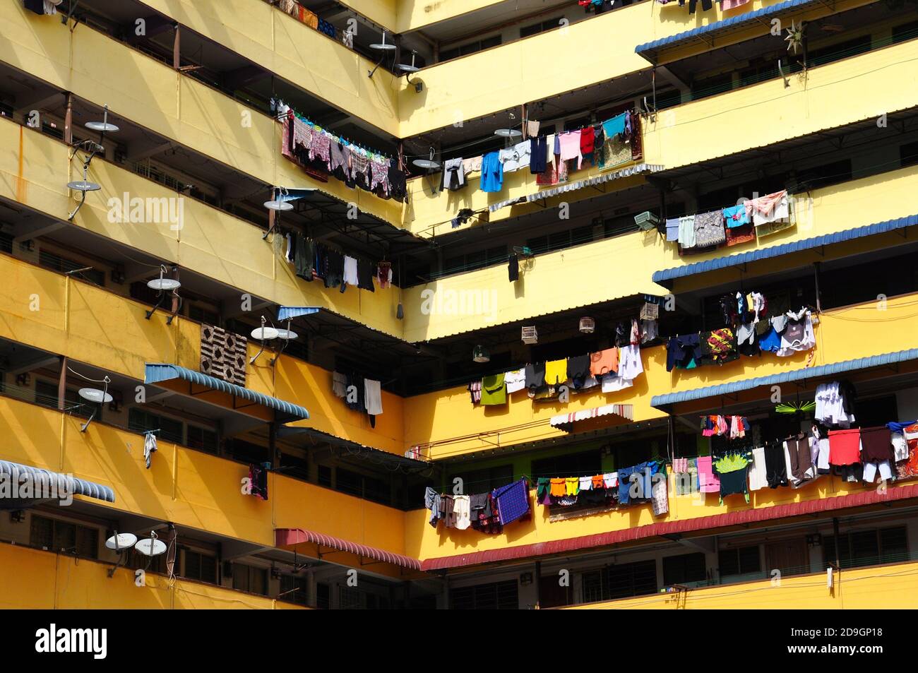 Farbenfrohe Wäsche, die auf den Balkonen eines Wohnblocks mit hoher Dichte in Asien zum Trocknen hängt. Stockfoto