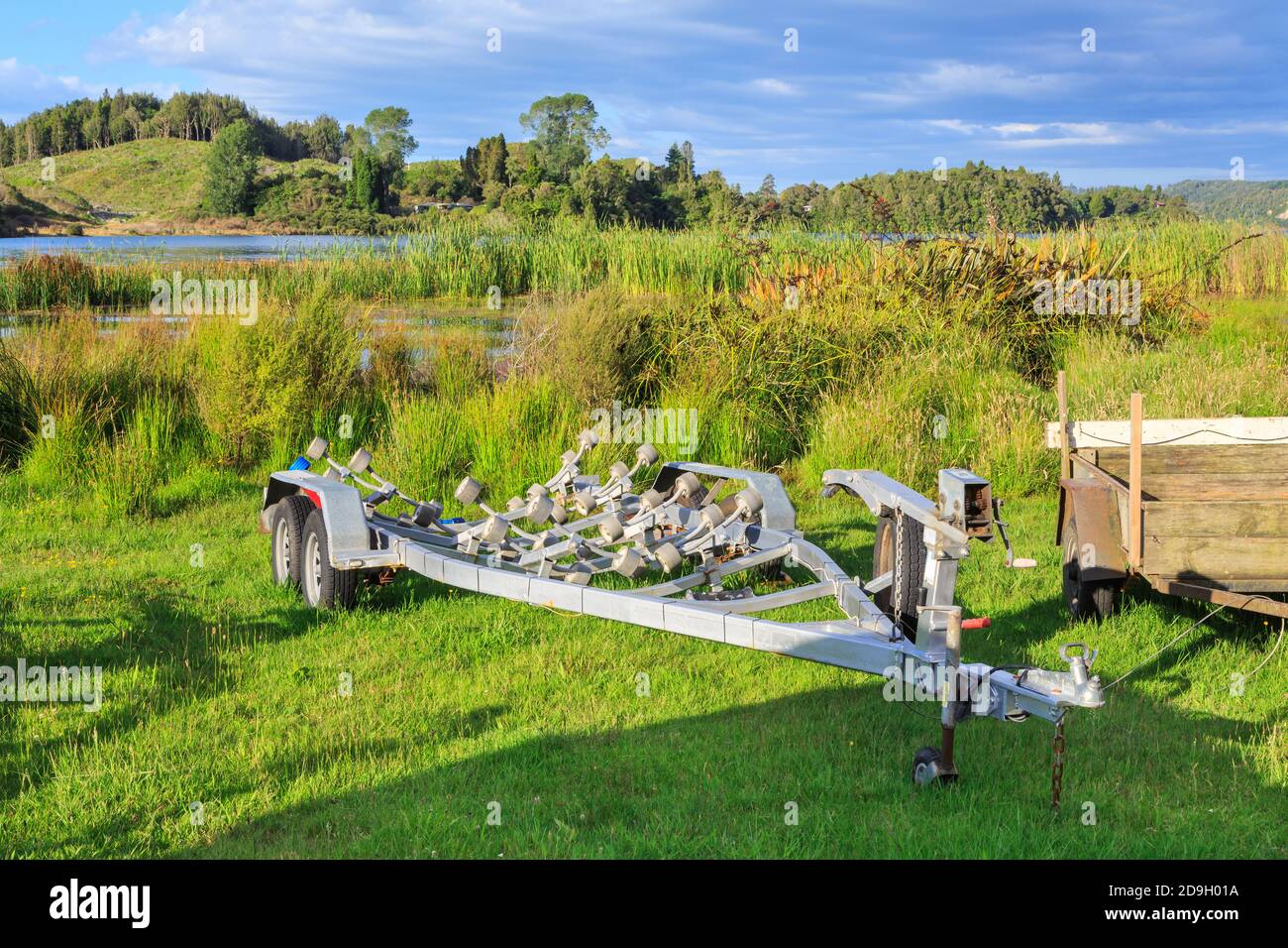 Ein Bootsanhänger auf dem grasbewachsenen Rand eines Sees. Fotografiert in Rotorua, Neuseeland Stockfoto