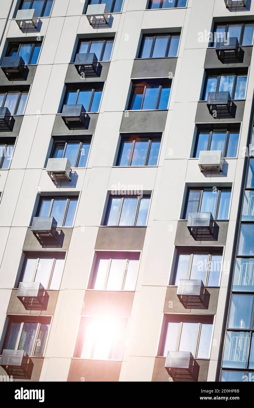 Fassade des Gebäudes mit Klimaanlagen. Sonnenlicht reflektiert im Fenster, vertikale Ansicht. Stockfoto