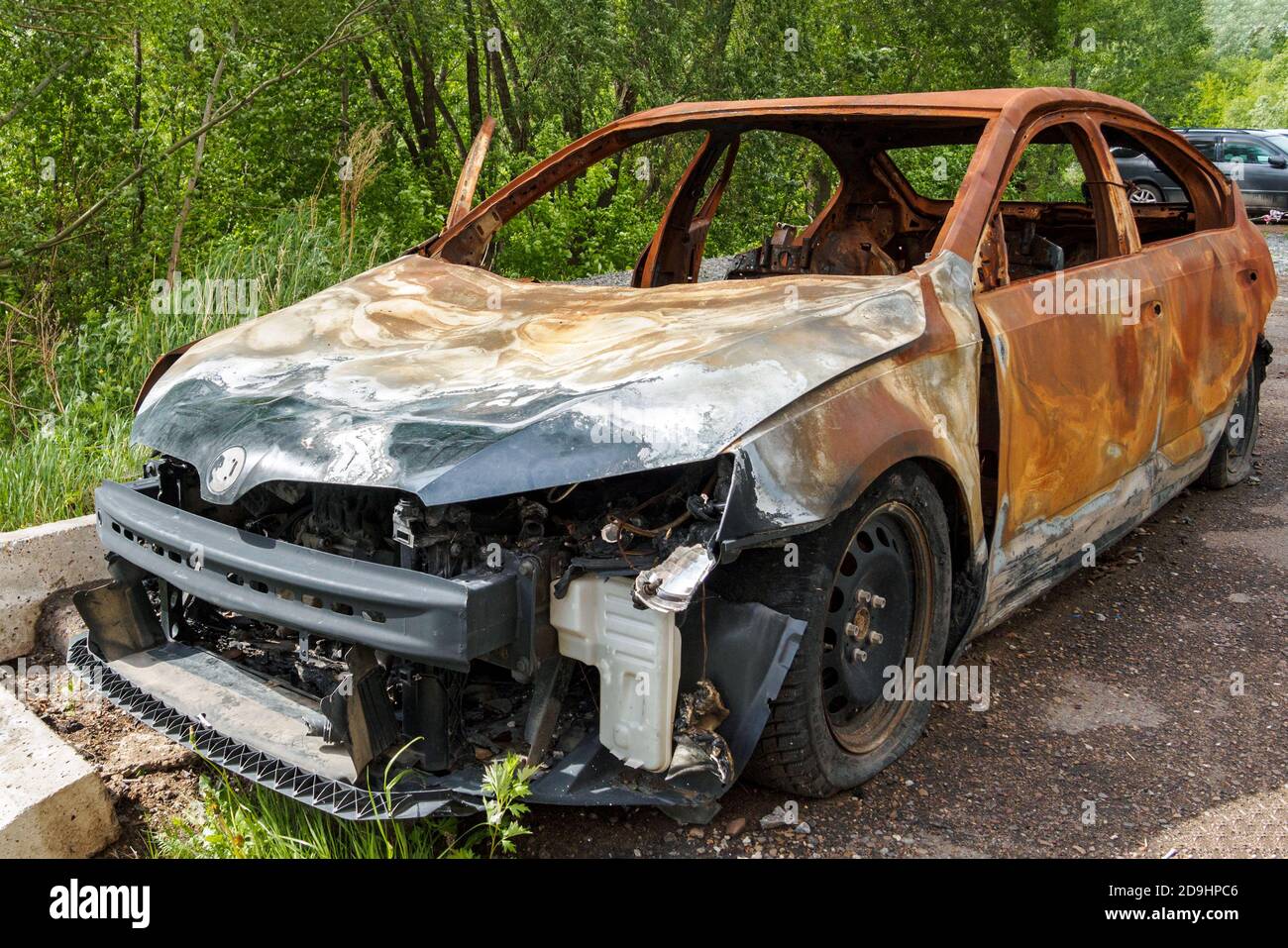 Vorderansicht eines verbrannten rostigen Pkw auf einem Sommertag Stockfoto