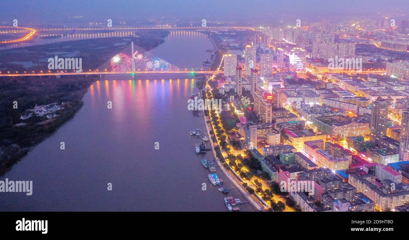 Eine Luftaufnahme des gesamten Stadtgebiets, das bei Nacht aufleuchtet und Lampen in Häusern, Automobillampen und Straßenlampen eingeschaltet werden, Harbin c Stockfoto
