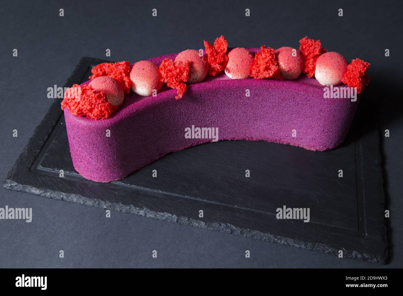 Nahaufnahme eines lila Mousse Kuchen mit Velours-Beschichtung und Rosa Mousse Kugeln Stockfoto