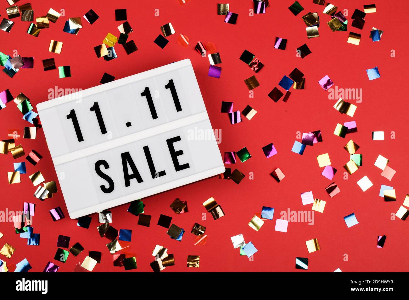 11.11 Verkaufstext auf weißem Leuchtkasten auf rotem Hintergrund mit Konfetti. Online-Shopping, Single-Day-Sale-Konzept. Kopiespeicherplatz in der Draufsicht Stockfoto