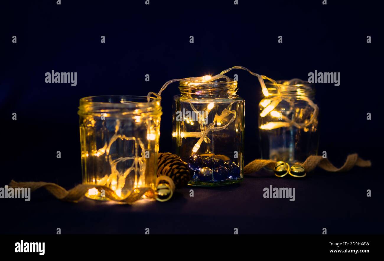 Lichterketten in recycelten Gläsern als festliche Feiertage Tischdekoration wiederverwendet, selektive Fokus. Stockfoto