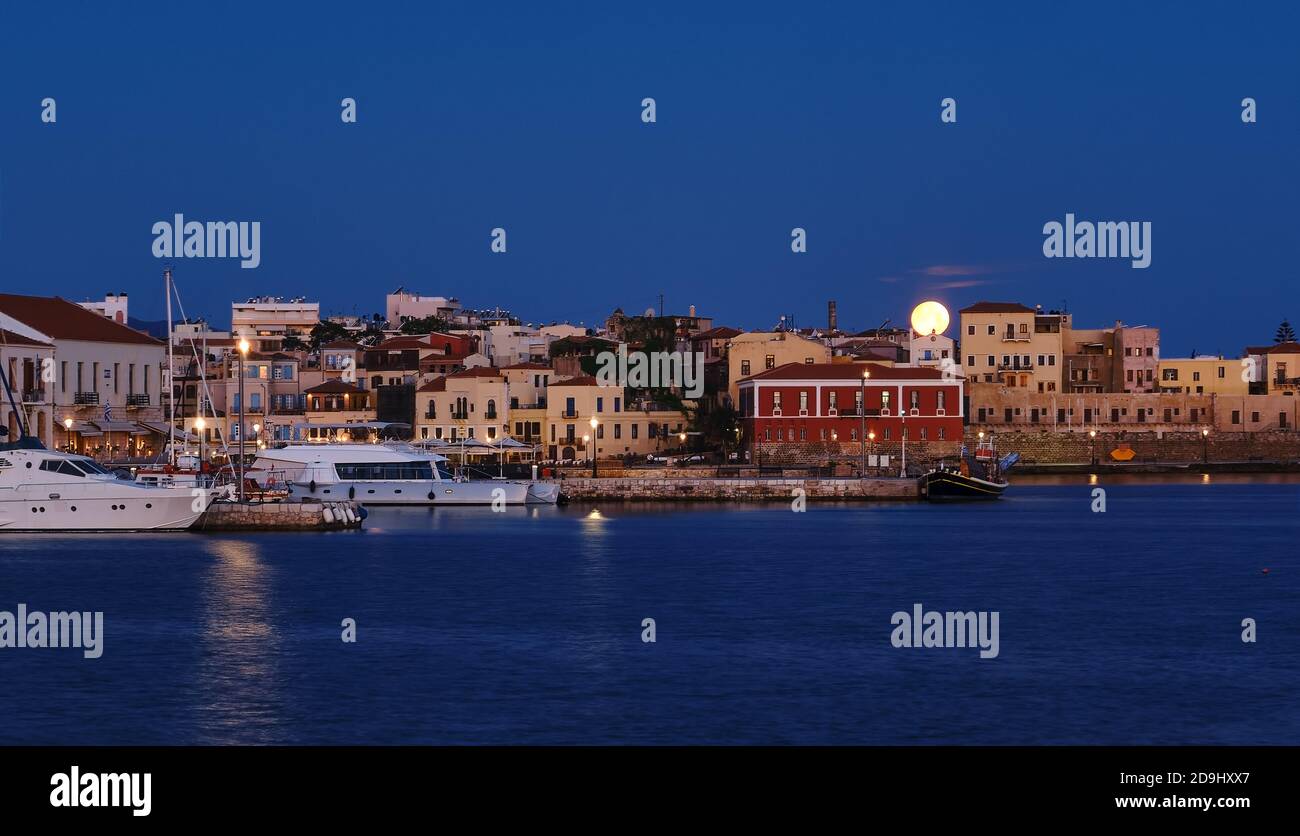 Vollmondeinstellung über Chania alten venezianischen Hafen. Nachtansicht der Piers, Boote und Maritime Museum von Kreta und Häuser über Marina. Stockfoto