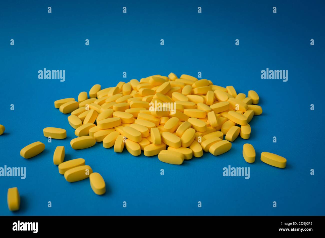 Pharmazie Industrie Produktionskonzept viele gelbe Pillen Tabletten auf blau Hintergrund Stockfoto