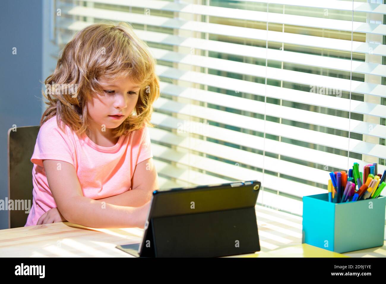 Intelligenter und attraktiver Junge mit Tablet auf dem Schreibtisch zu Hause. Online-Bildungskonzept. Bildung für Kinder, Wissen. Stockfoto