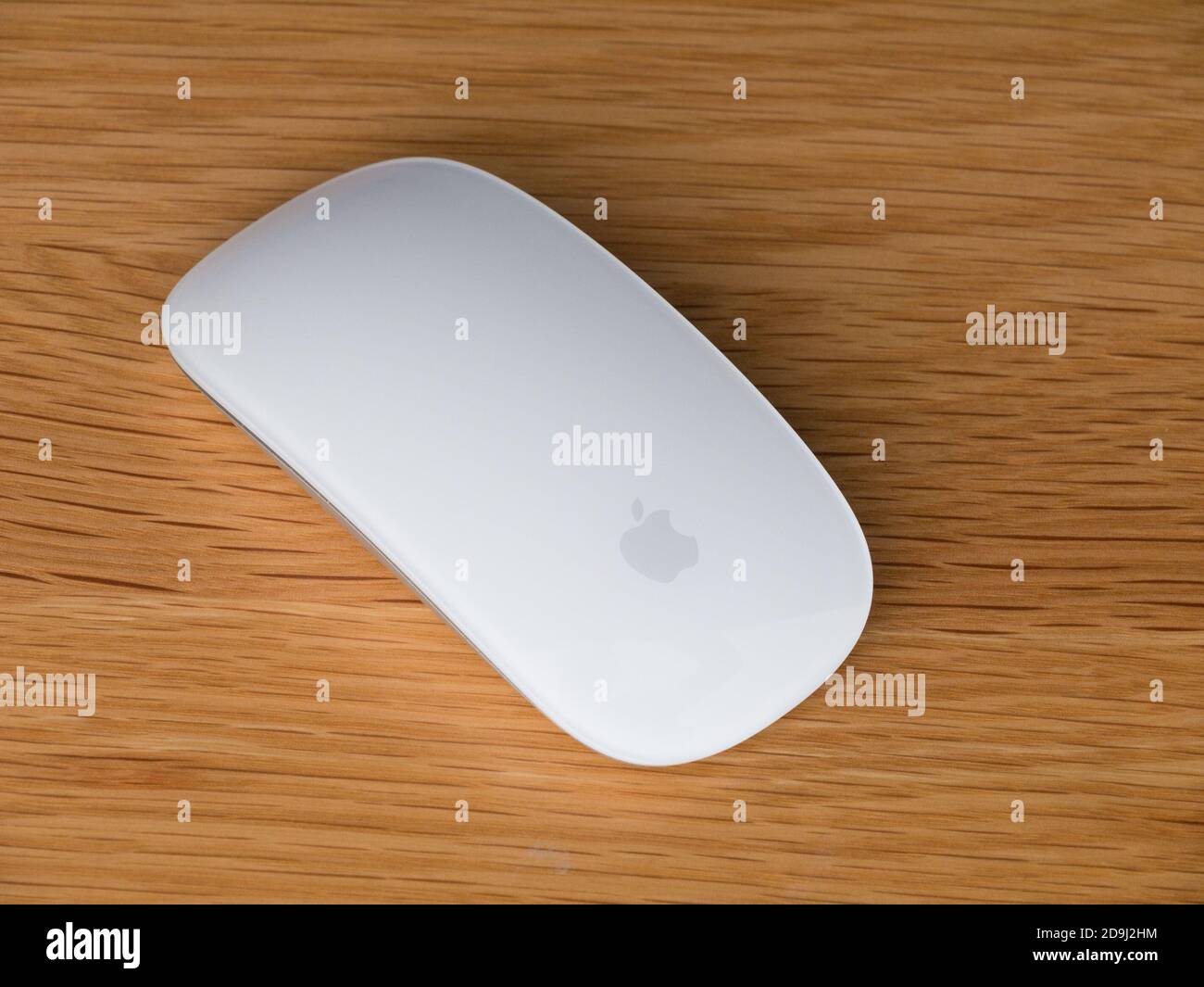 Nahaufnahme der weißen kabellosen/Bluetooth-/kabellosen Apple Magic Mouse 2 auf einer hölzernen Tischoberfläche. Stockfoto