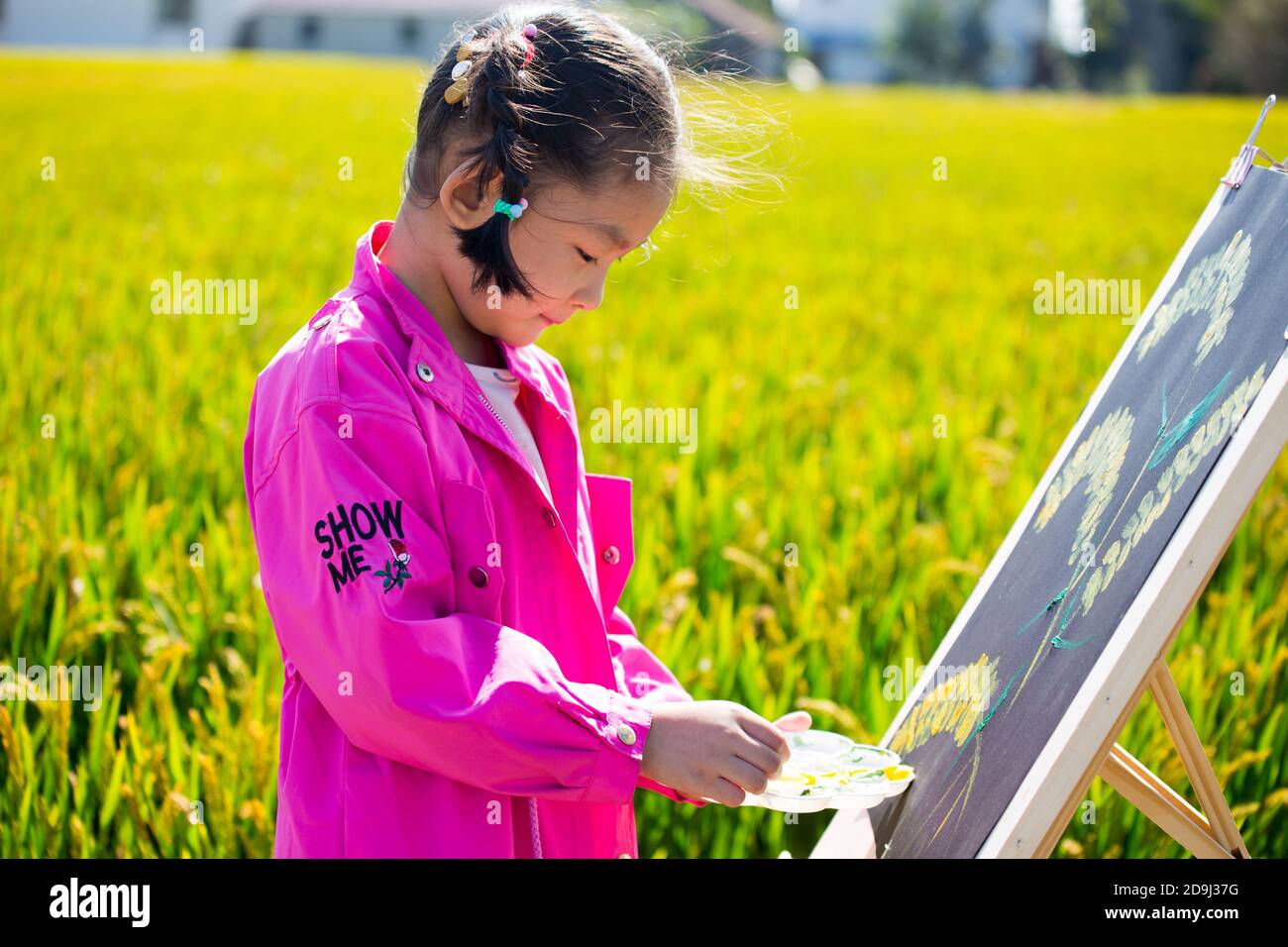 Eine Kindergärtnerin nimmt Kinder mit, um in den goldenen Reisfeldern zu malen, um den kommenden Herbst in Rugao City, der ostchinesischen Provinz Jiangsu, zu begrüßen. Stockfoto