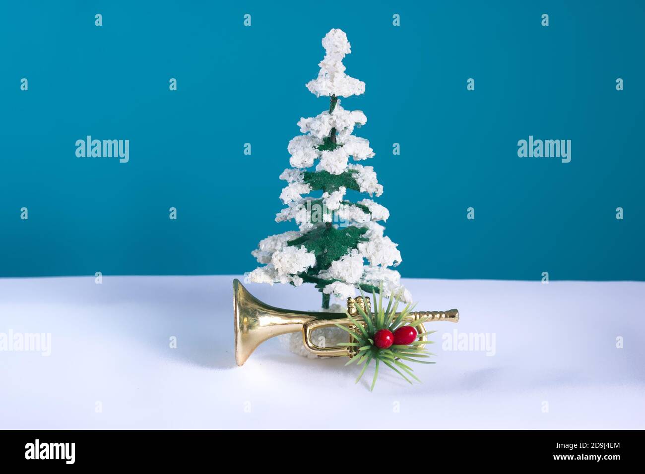 Schneebedeckter Baum mit Trompete festlich mit einem blauen Hintergrund verziert. Weihnachten Stillleben für Musiker. Stockfoto