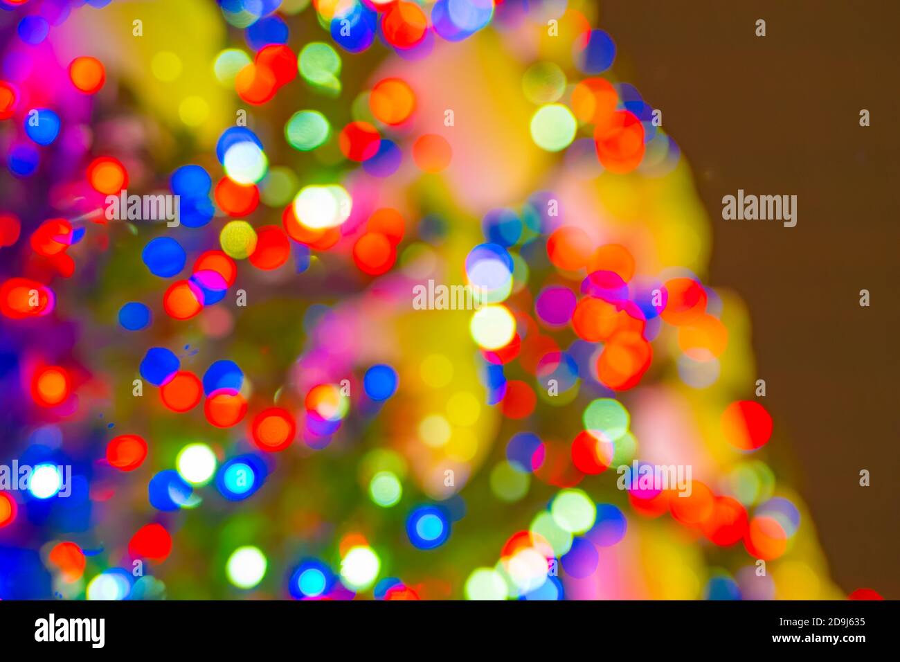 Verschwommenes warmes Neujahrslicht am dunklen Himmel, unfokussierter Hintergrund Stockfoto