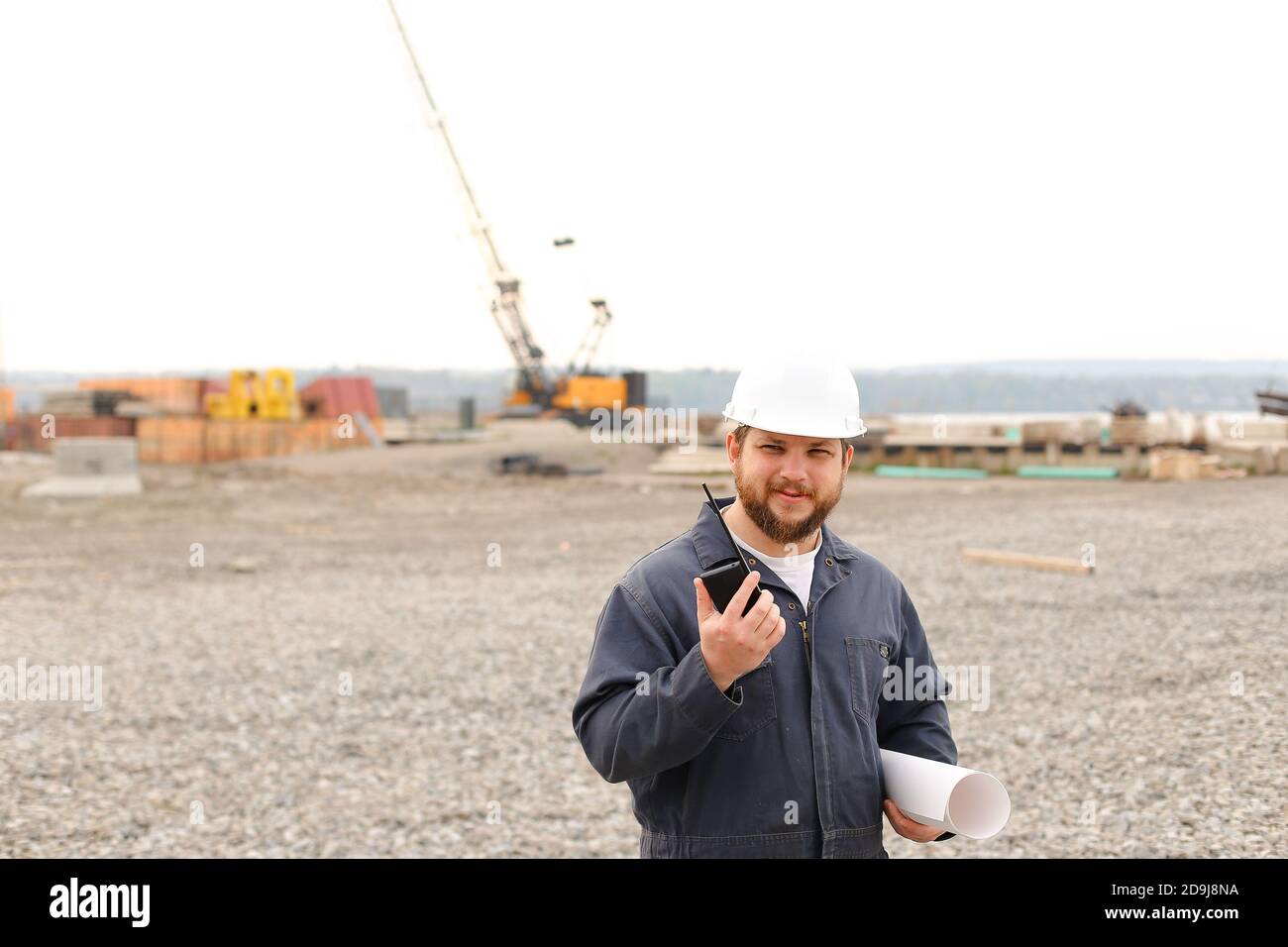 Vorarbeiter auf der Baustelle, im Gespräch mit VHF-Walkie-Talkie und mit Blaupausen. Stockfoto