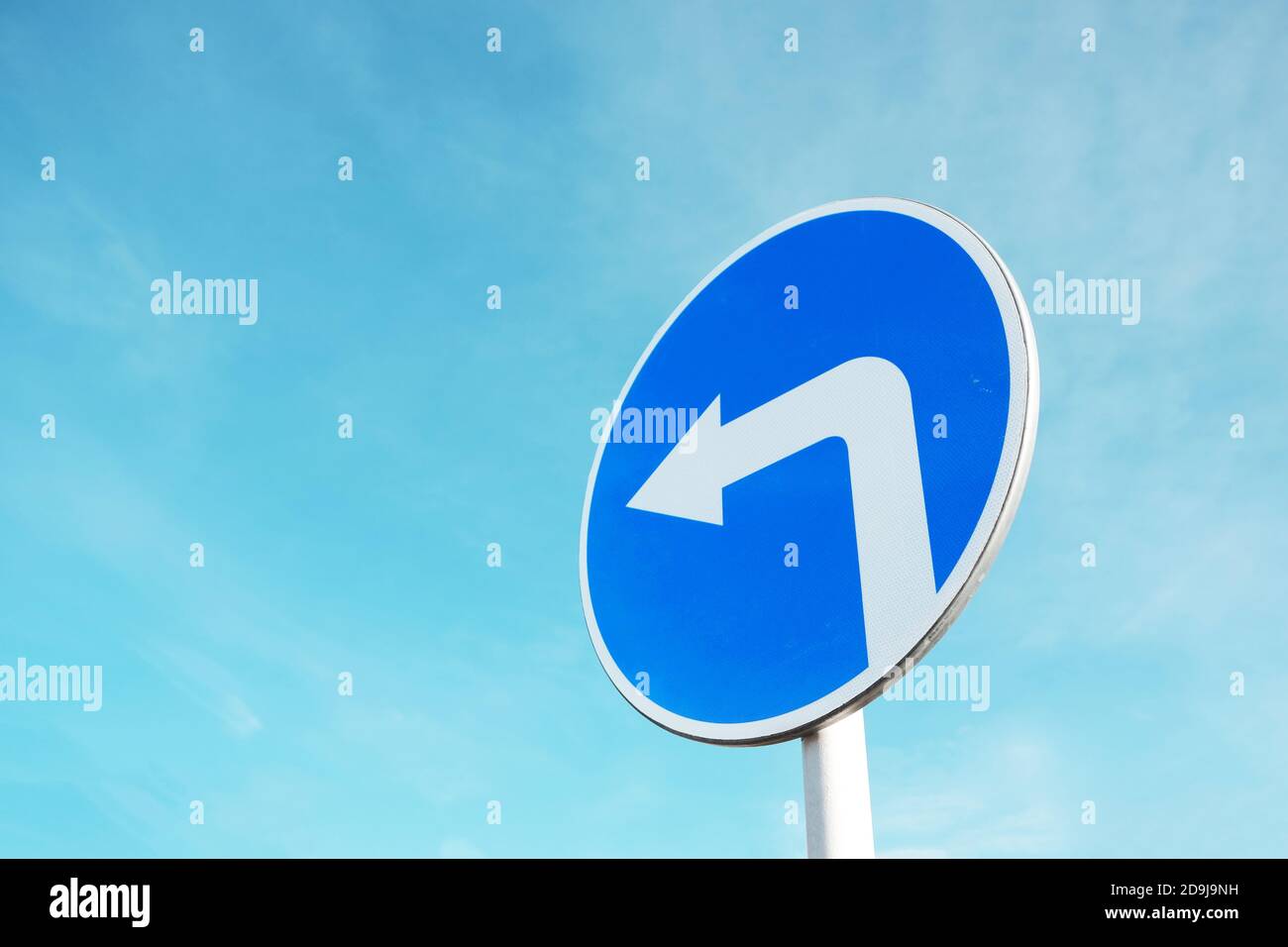 Blaues Verkehrsschild, das nach links abbiegt. Stockfoto