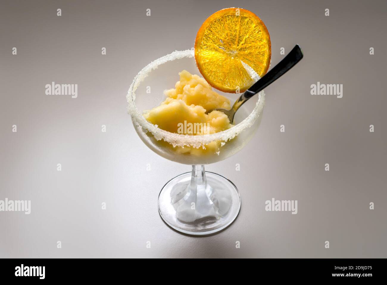 Orangenfruchteis in einem Tasse Glas mit karamellisiert Orange Scheibe und Teelöffel Stockfoto