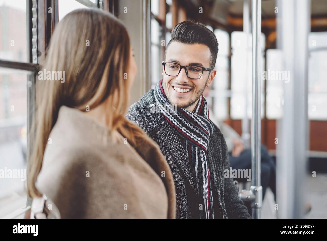 Glückliches Paar, das Gespräch hat, während man im Bus zur Arbeit geht - Junge Leute, die in der alten Straßenbahn Transport Stockfoto