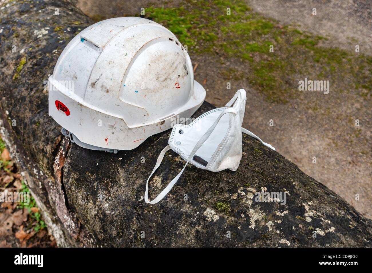 Arbeiter Sicherheitshelm und Gesichtsmaske an der Wand links Stockfoto