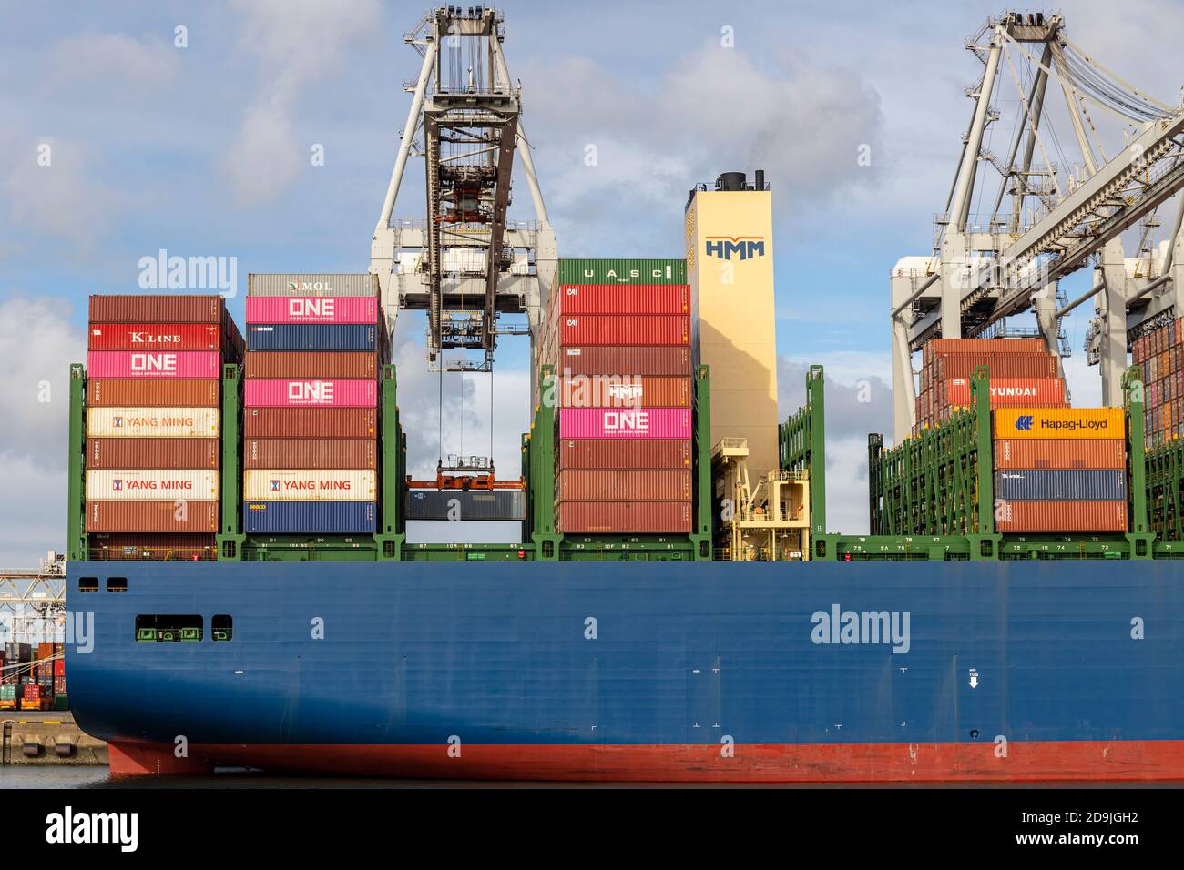 Großes Containerschiff der Gülsün-Klasse wird im Hafen von Rotterdam verladen. Stern des Schiffes mit einem Container auf dem Kran, der in das Schiff abgesenkt wird. Stockfoto