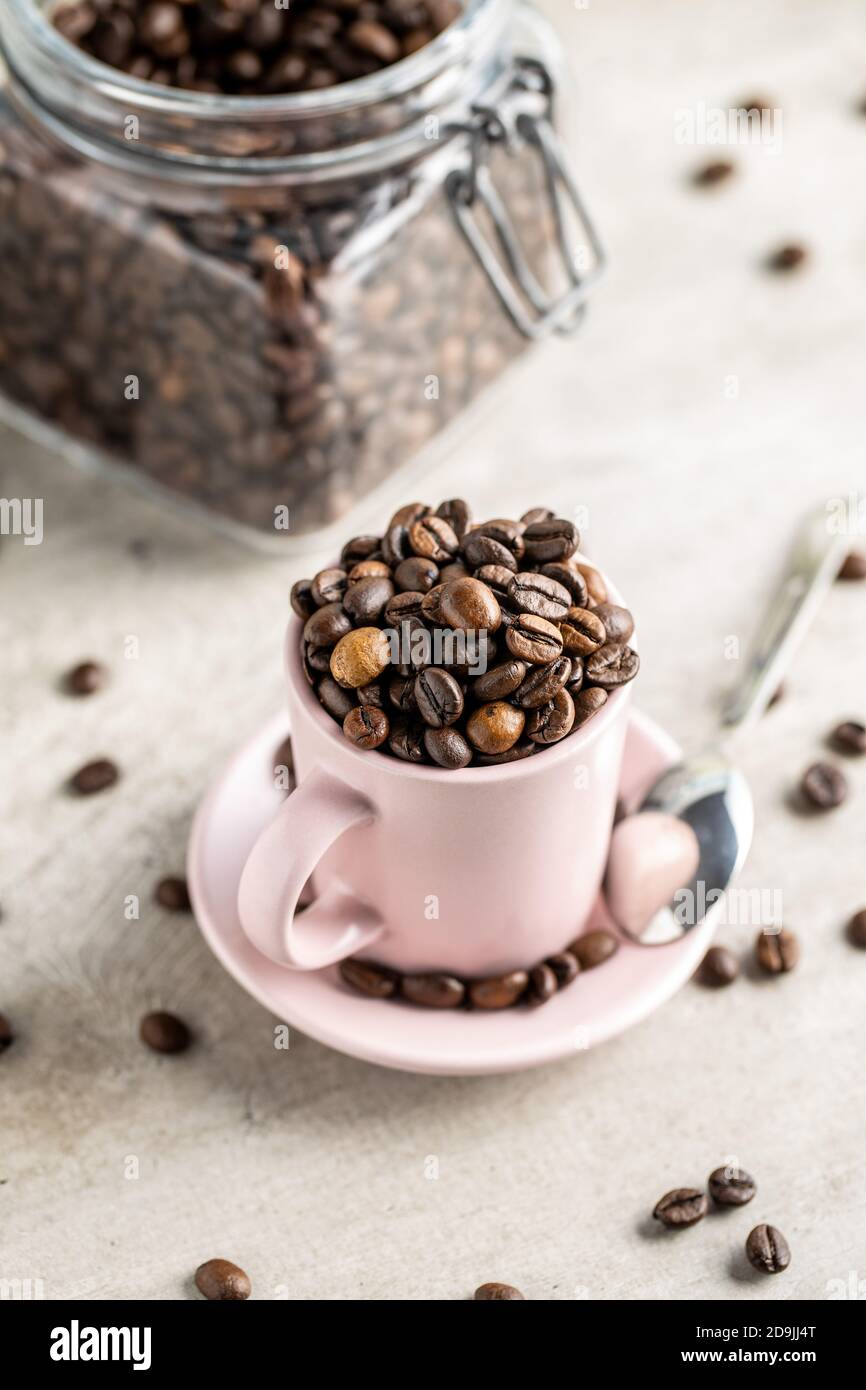 Geröstete Kaffeebohnen in Tasse auf weißem Tisch. Stockfoto