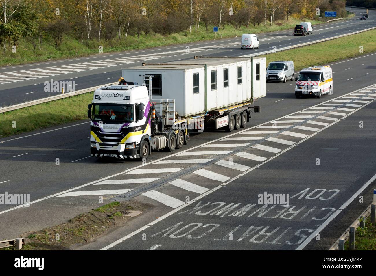 Ein LKW mit großer Ladung, gefolgt von einem Begleitfahrzeug, Autobahn M40, Warwickshire, Großbritannien Stockfoto