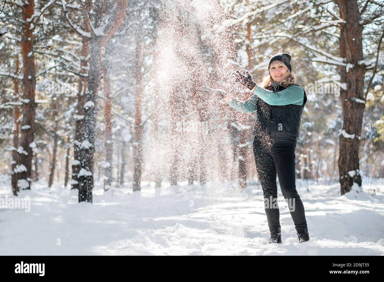 Frau von Schneeflocken umgeben. Modell wirft Schnee im Winterwald. Stockfoto