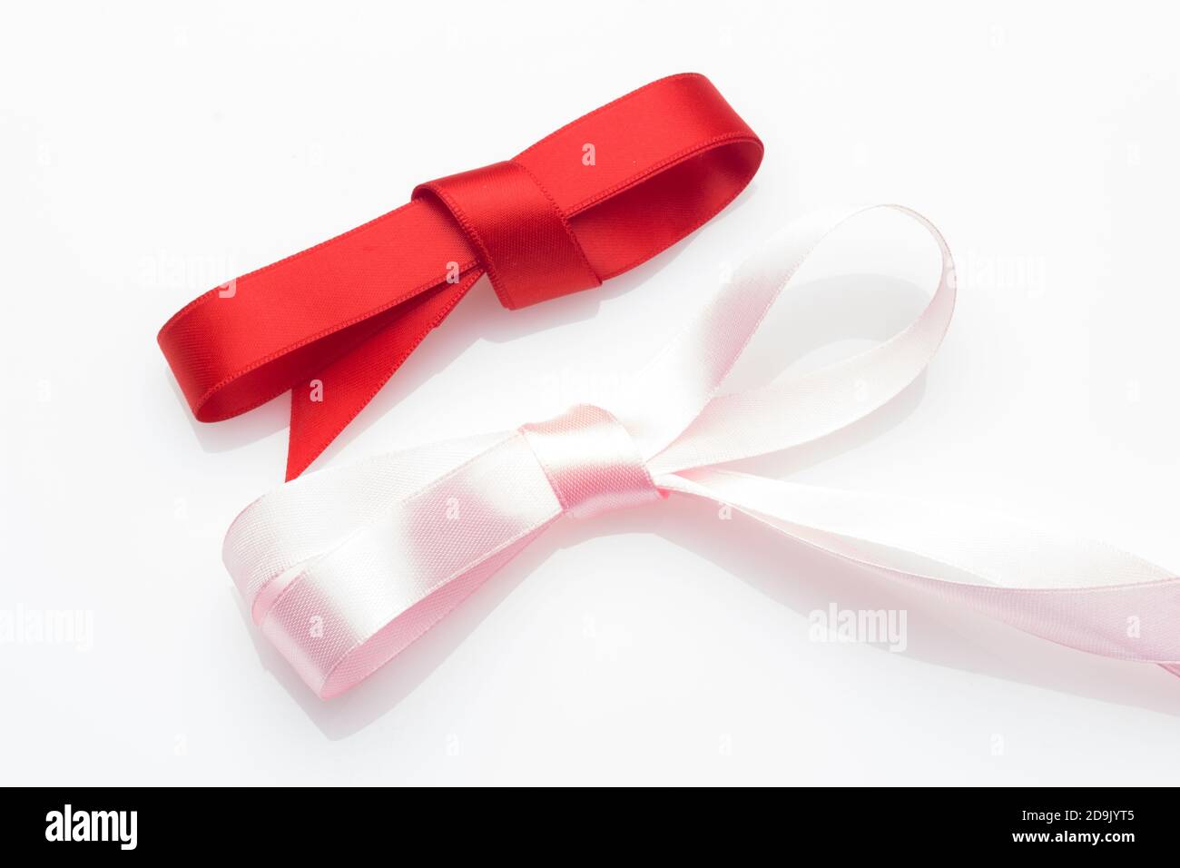 Farbige Schleife zum Verpacken von Weihnachtsgeschenken oder Jubiläumsgeschenken: Hübscher Knoten, der eine Geschenkschleife auf einem hellen farbigen Stoff erzeugt Stockfoto