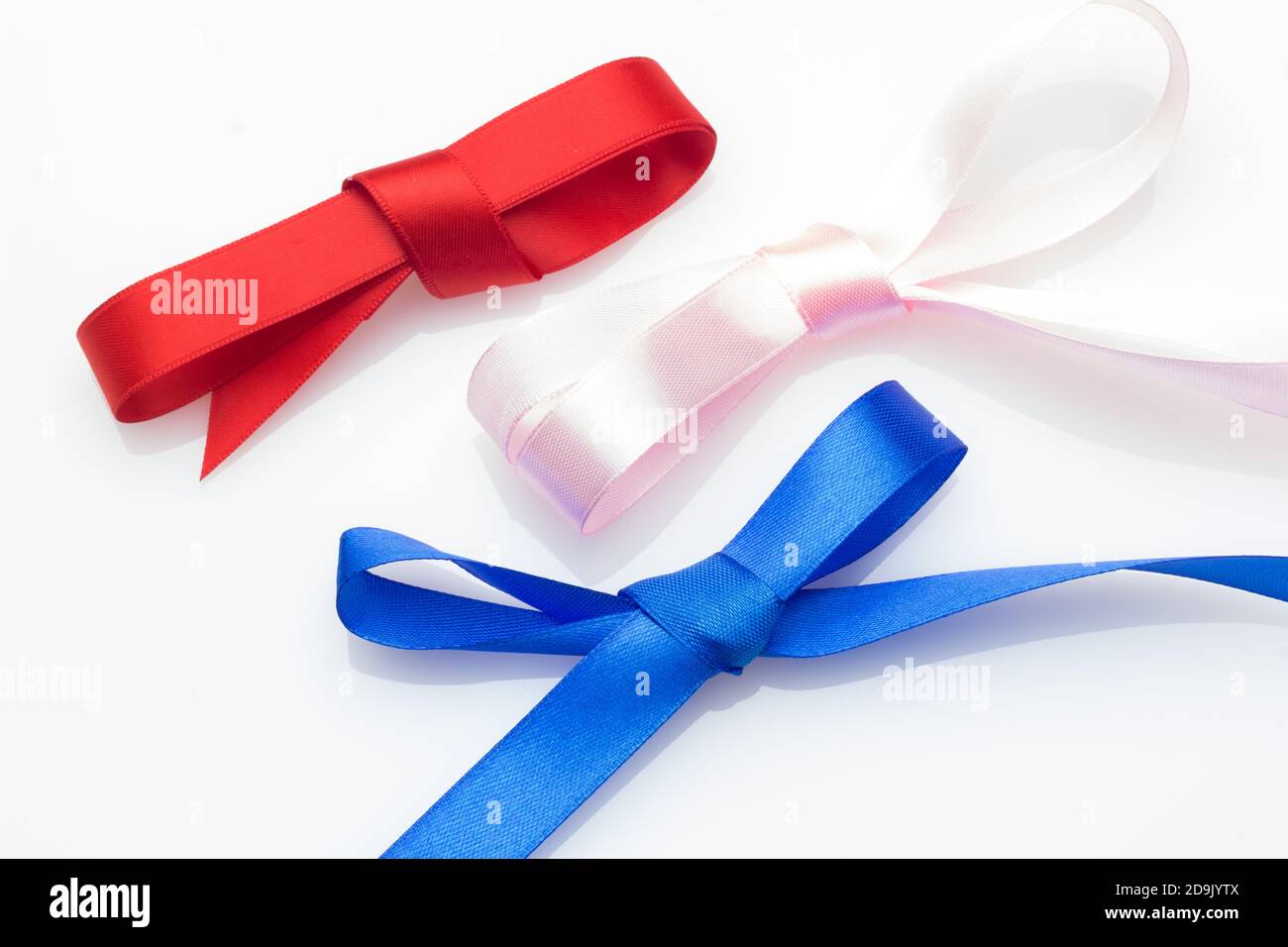 Farbige Schleife zum Verpacken von Weihnachtsgeschenken oder Jubiläumsgeschenken: Hübscher Knoten, der eine Geschenkschleife auf einem hellen farbigen Stoff erzeugt Stockfoto