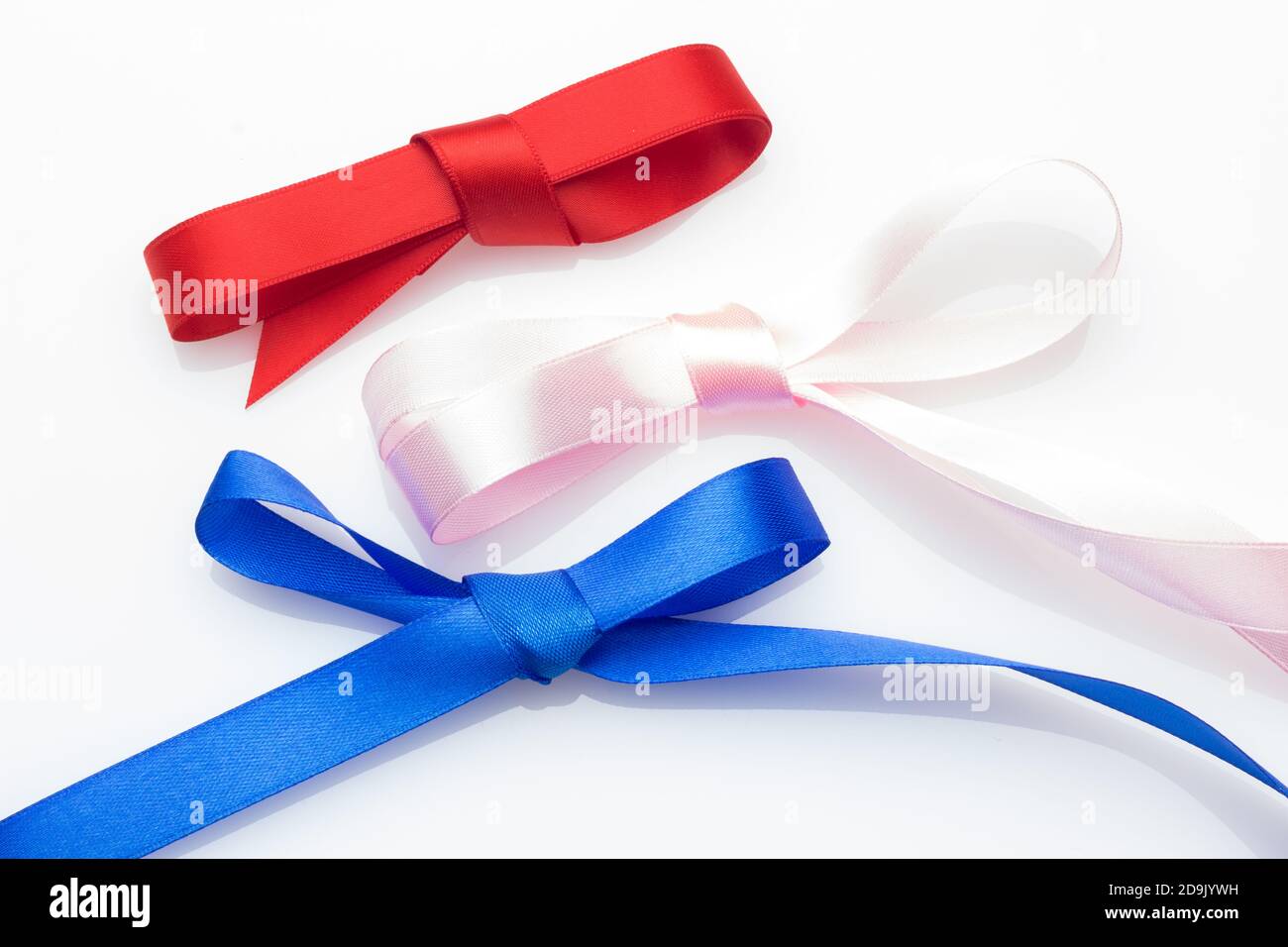 Farbige Schleife zum Verpacken von Weihnachtsgeschenken oder Jubiläumsgeschenken: Hübscher Knoten, der eine Geschenkschleife auf einem hellen farbigen Stoff erzeugt Stockfoto