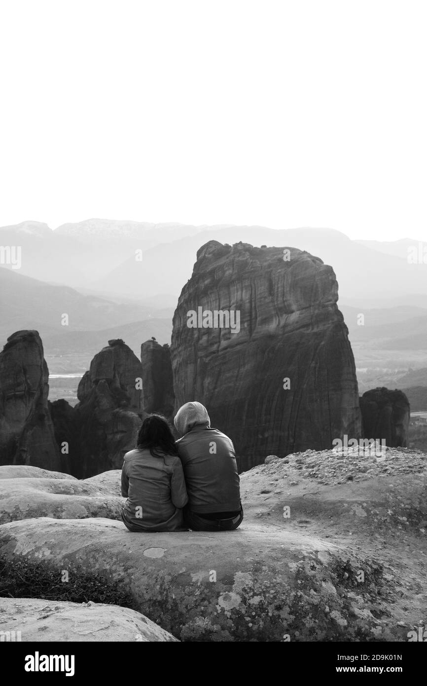 Ein Paar sitzt und genießt die Aussicht von einem der Meteora Felsen. UNESCO-Weltkulturerbe Meteora, Griechenland Stockfoto