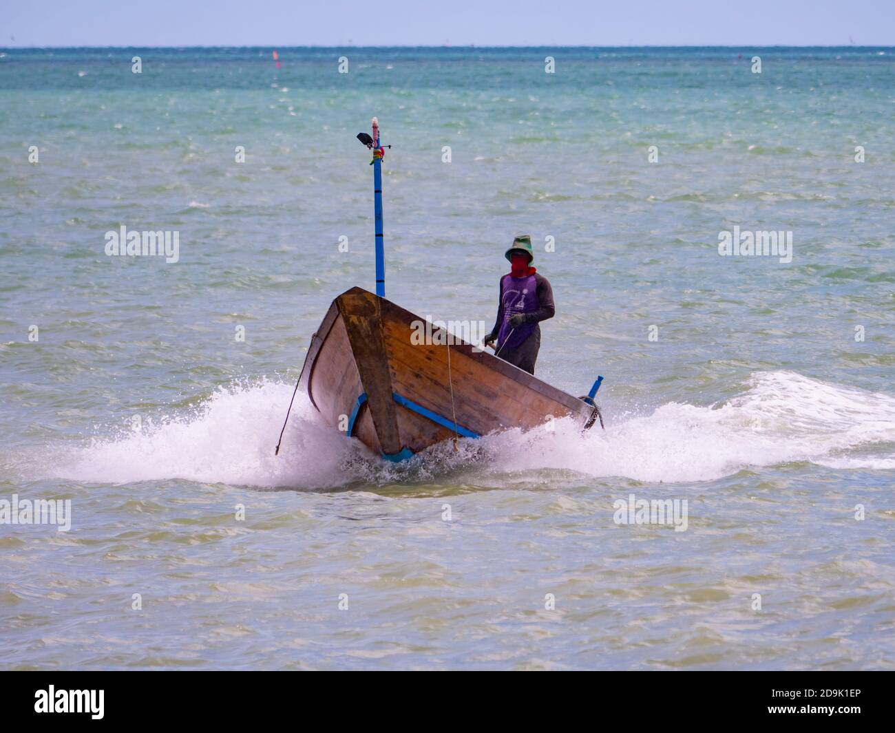 Fischer, der nach einem regnerischen Tag auf See in der Provinz Rayong in Thailand mit seinem traditionellen Holzboot im Hafen ankommt. Stockfoto