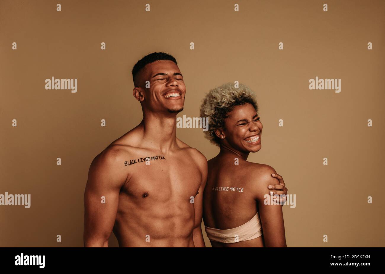 Lächelnder afroamerikanischer Mann und Frau stehen zusammen auf braunem Hintergrund. Paar mit der Black Lives Matter Kampagne verbunden. Stockfoto