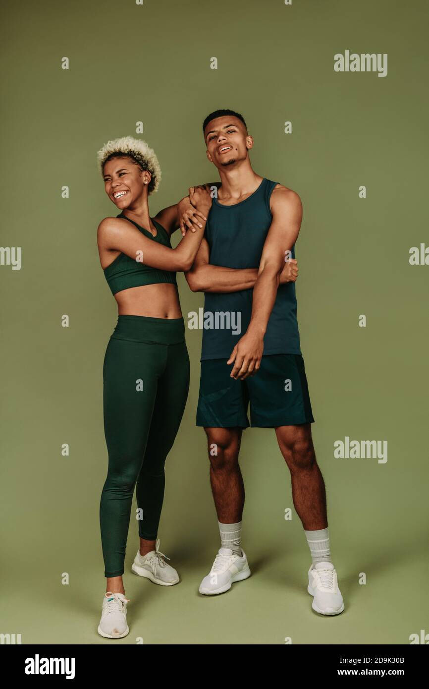 Paar in Fitness tragen stehen zusammen auf grünem Hintergrund. Fröhliche Fitness Frau steht mit männlichen Athleten. Stockfoto