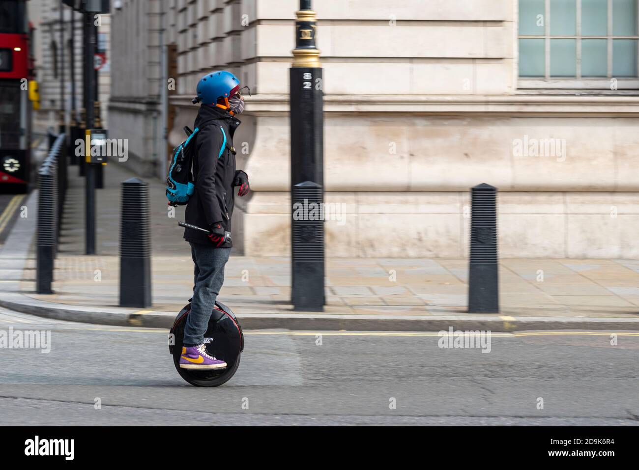 Elektro-Einrad Fahrer in Whitehall, London, Großbritannien. Self balancing, ein Rad persönlichen Transport Fahrer Reiten auf der Straße, trägt Gesichtsmaske und Helm Stockfoto