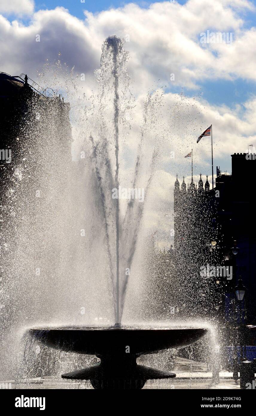 London, England, Großbritannien. Hintergrundbeleuchteter Brunnen am Trafalgar Square. Häuser des Parlaments im Hintergrund Stockfoto