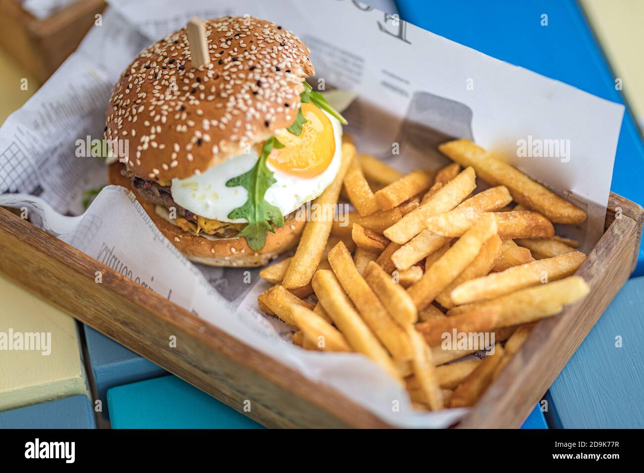 Hamburger und Pommes. Riesenburger mit pommes Frites in Holzschüsselteller. Gourmet hausgemachter Hamburger in der Außenterrasse des Restaurants Stockfoto