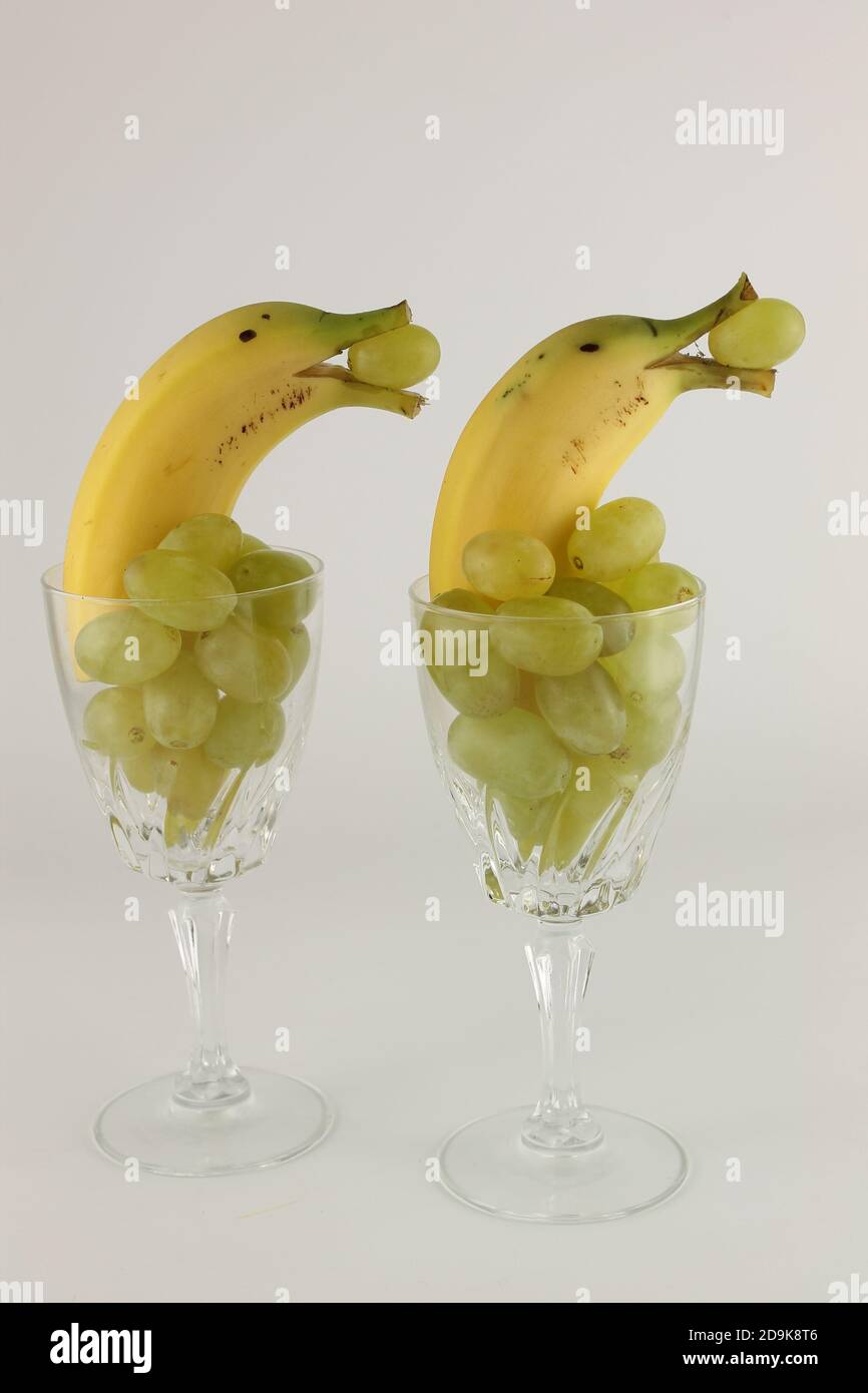 Bananen in gefälschtem Glas mit Trauben arrangieren wie Delphine im Wasser, vegetarisches Weihnachtsessen Stockfoto