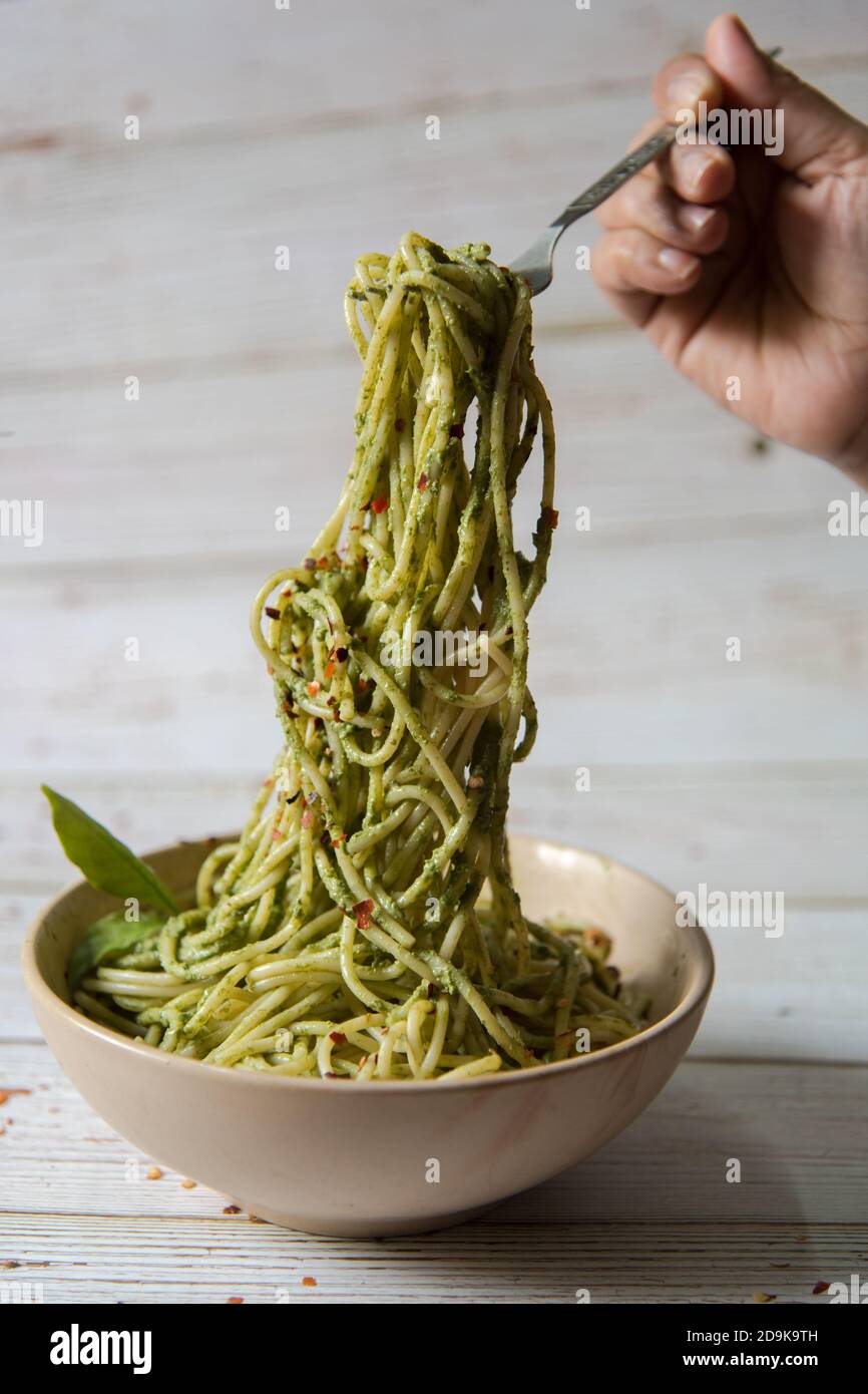 Hände servieren Pasta in Pesto-Sauce aus einer Schüssel Stockfoto